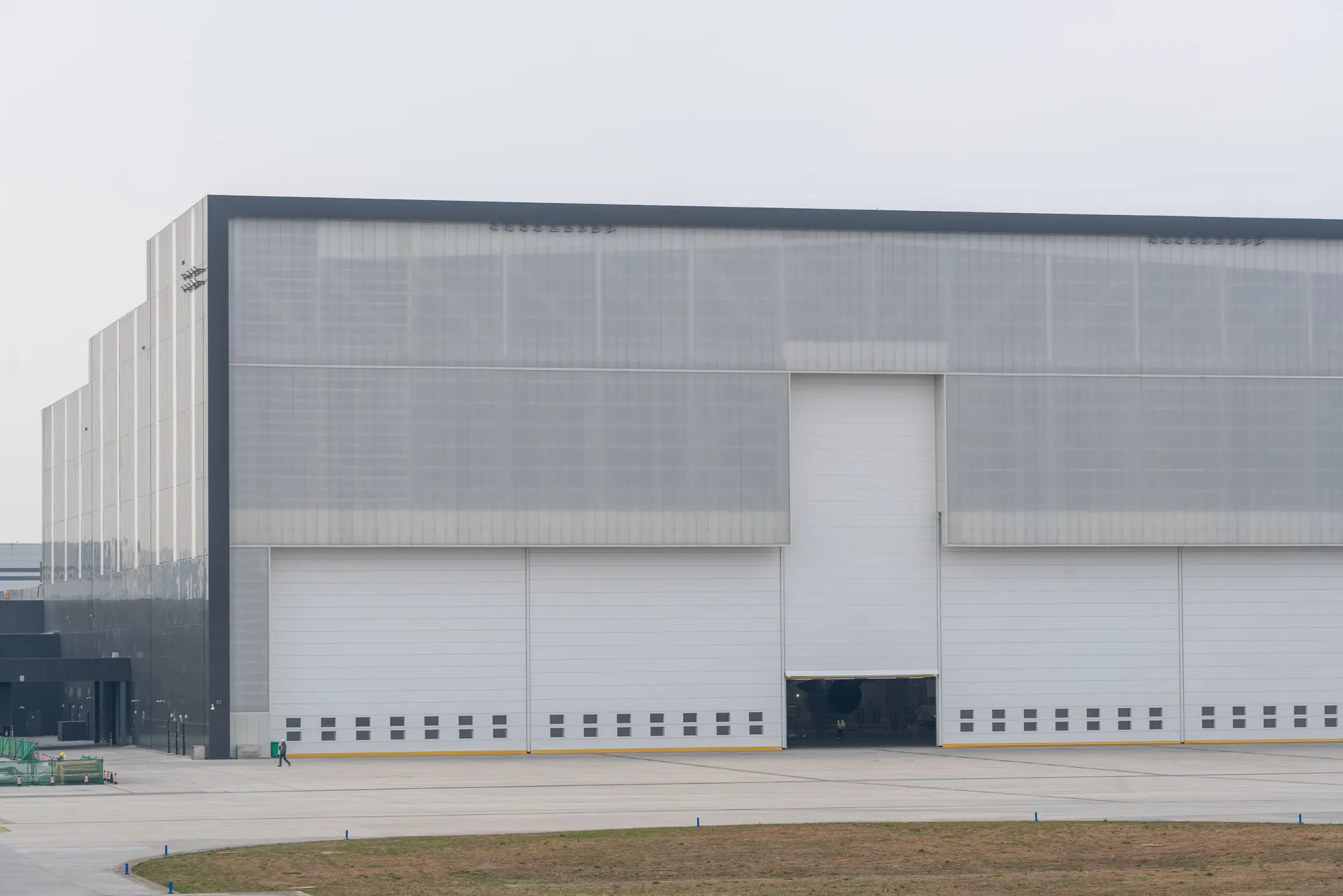 A modern single-storey logistics warehouse with loading docks under an overcast sky